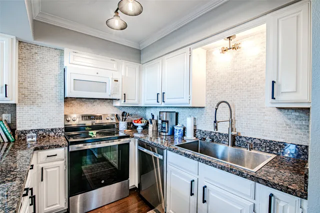 a kitchen with stainless steel appliances granite countertop a sink a stove and cabinets