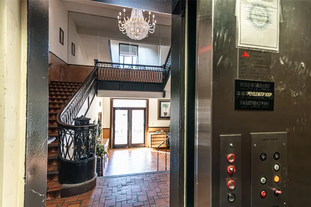 a view of a hallway with wooden floor and dining room with windows