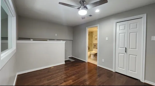 an empty room with wooden floor cabinet and windows