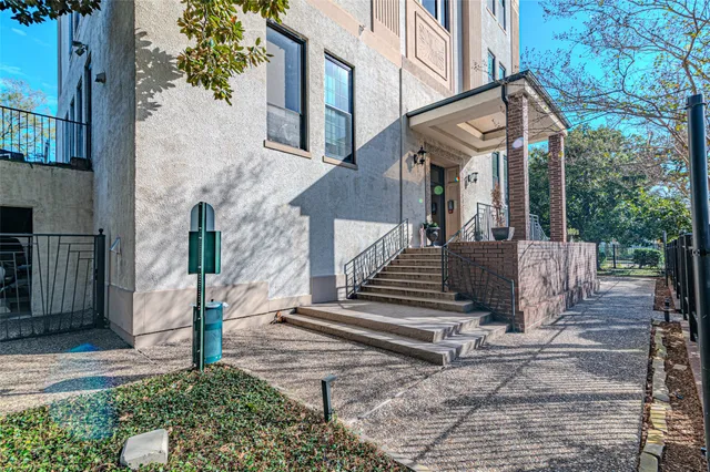a view of a building with a small yard and large tree