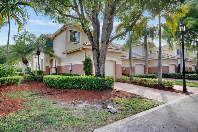 a front view of a house with a garden and a tree