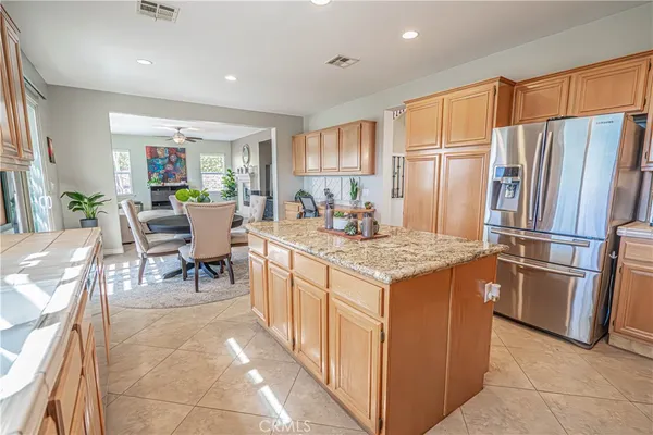 a open kitchen with kitchen island granite countertop a large stove a sink and white cabinets
