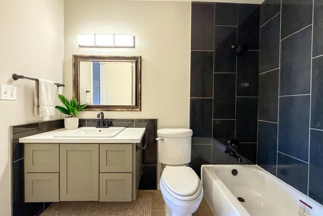 a bathroom with a granite countertop toilet a sink and a mirror