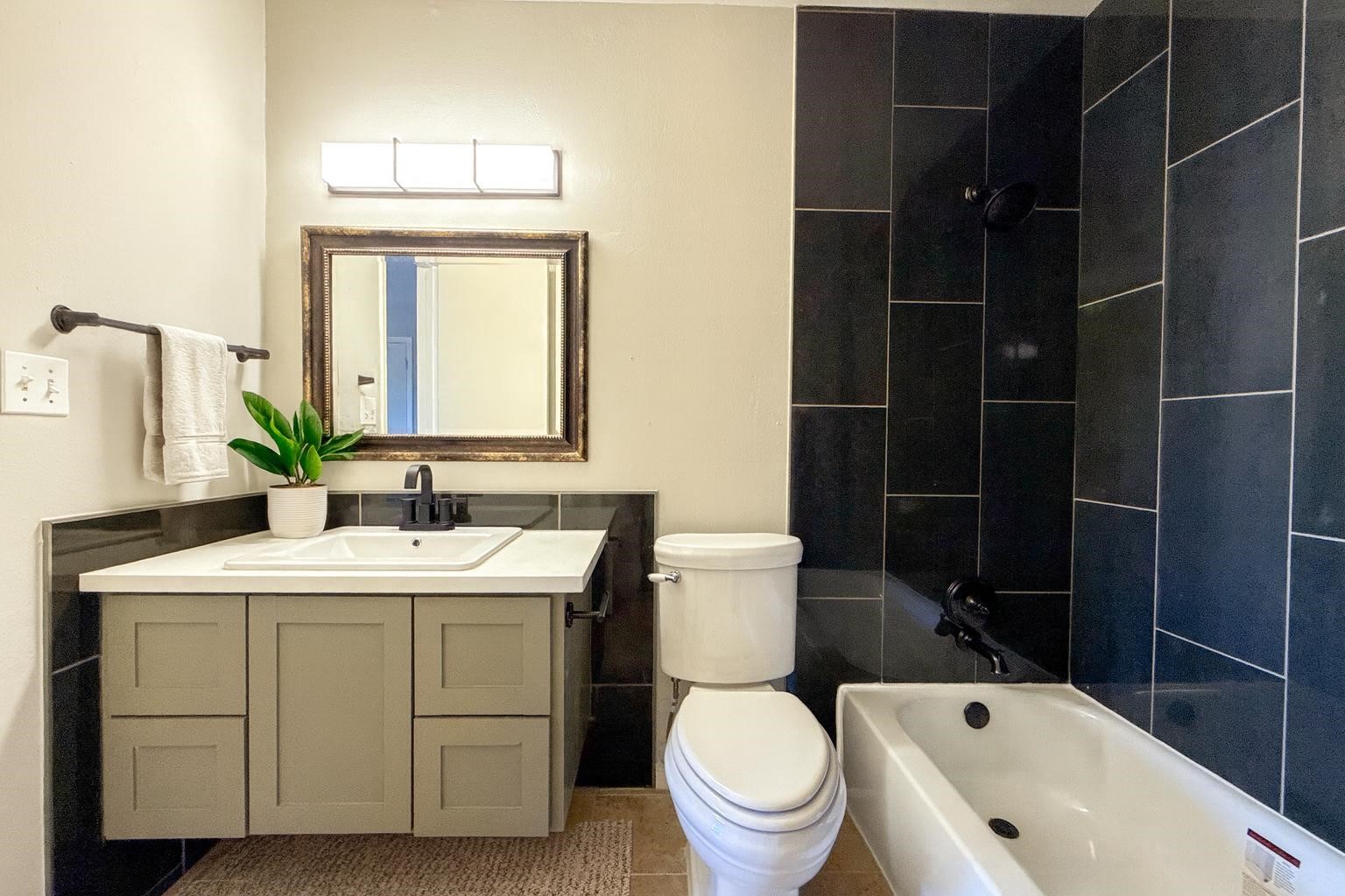 a bathroom with a granite countertop toilet a sink and a mirror