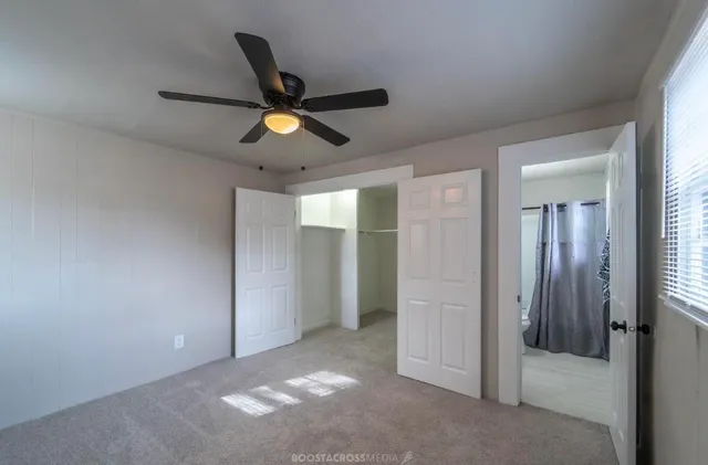 an empty room with closet and a chandelier fan