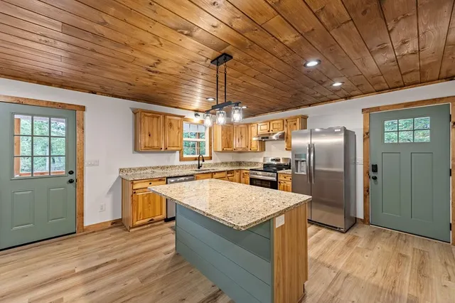 a kitchen with kitchen island granite countertop a sink stove and refrigerator