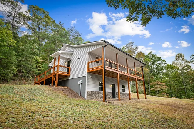 a backyard of a house with wooden deck and outdoor seating