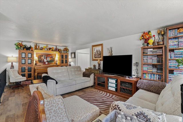 1025 Bristol Road Fruit Heights, UT 84037 - Photo 6 of 20 Spacious common area featuring wood-finish flooring, light-toned walls, and a large entertainment console