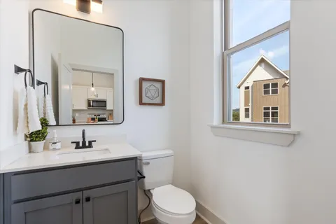 a bathroom with a toilet a sink a mirror and a window