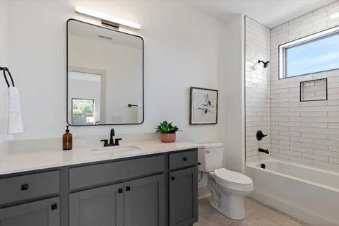 a bathroom with a toilet a sink a tub and mirror