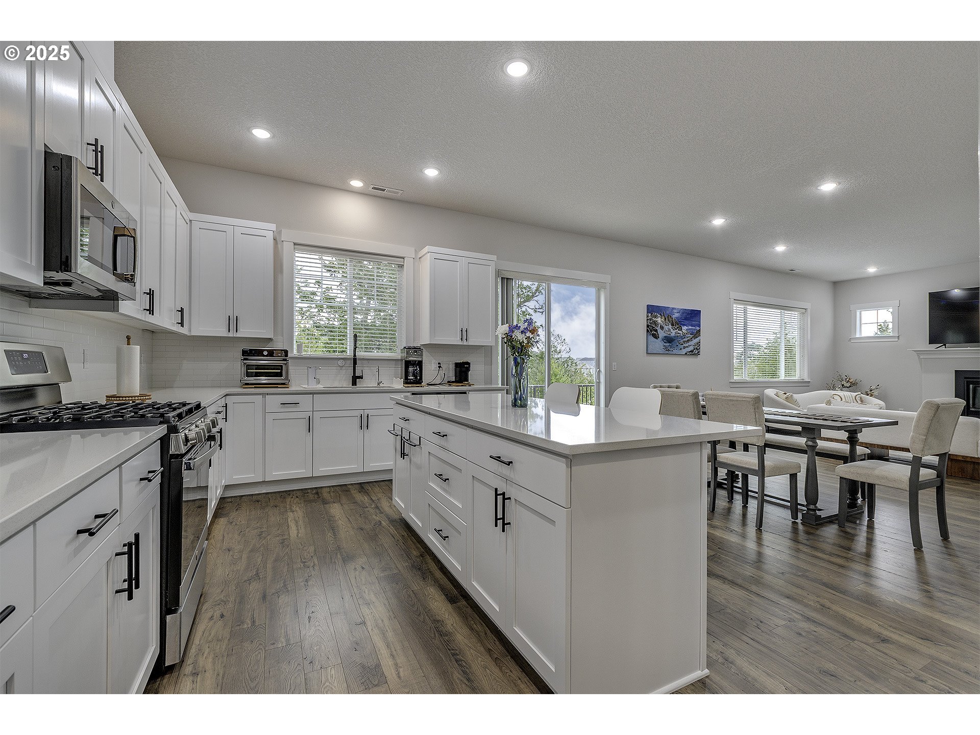 15080 Northwest Legend Street Portland, OR 97229 - Photo 12 of 38 a kitchen with stainless steel appliances granite countertop a stove top oven a sink dishwasher a dining table and chairs with wooden floor