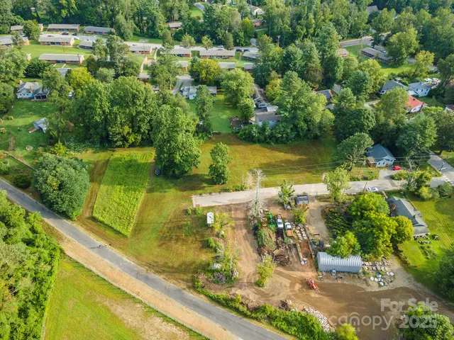 an aerial view of residential houses with outdoor space and trees all around