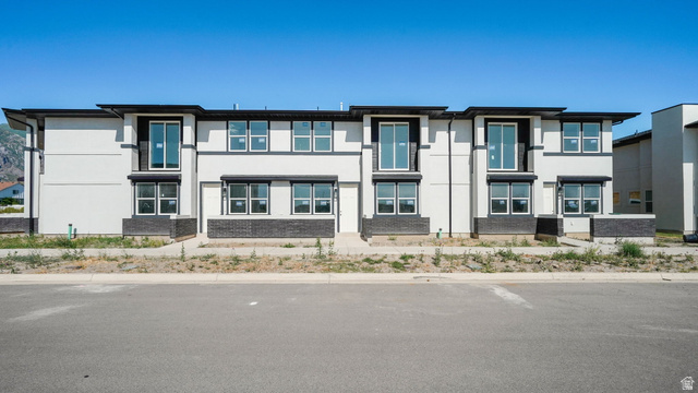 717 South Harrison Drive West Springville, UT 84663 - Photo 1 of 31 Contemporary townhome-style exterior featuring a white facade with dark trim, multiple large windows, and a black brick-like foundation detail