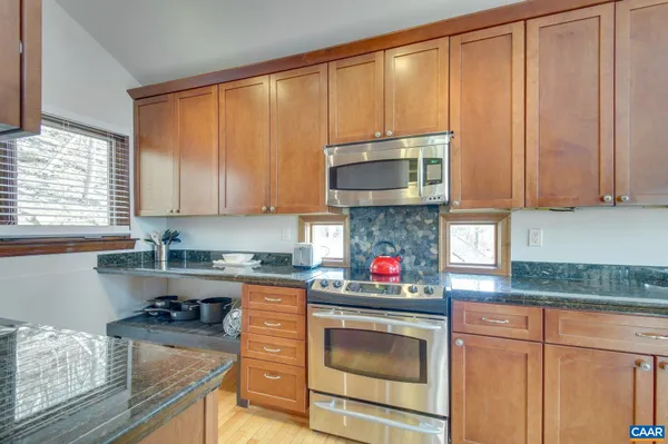 a kitchen with granite countertop a sink a stove and cabinets