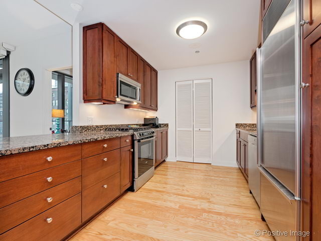 60 East Monroe Street, Unit 1906 Chicago, IL 60603 - Photo 12 of 20 a large kitchen with granite countertop a refrigerator and a stove top oven