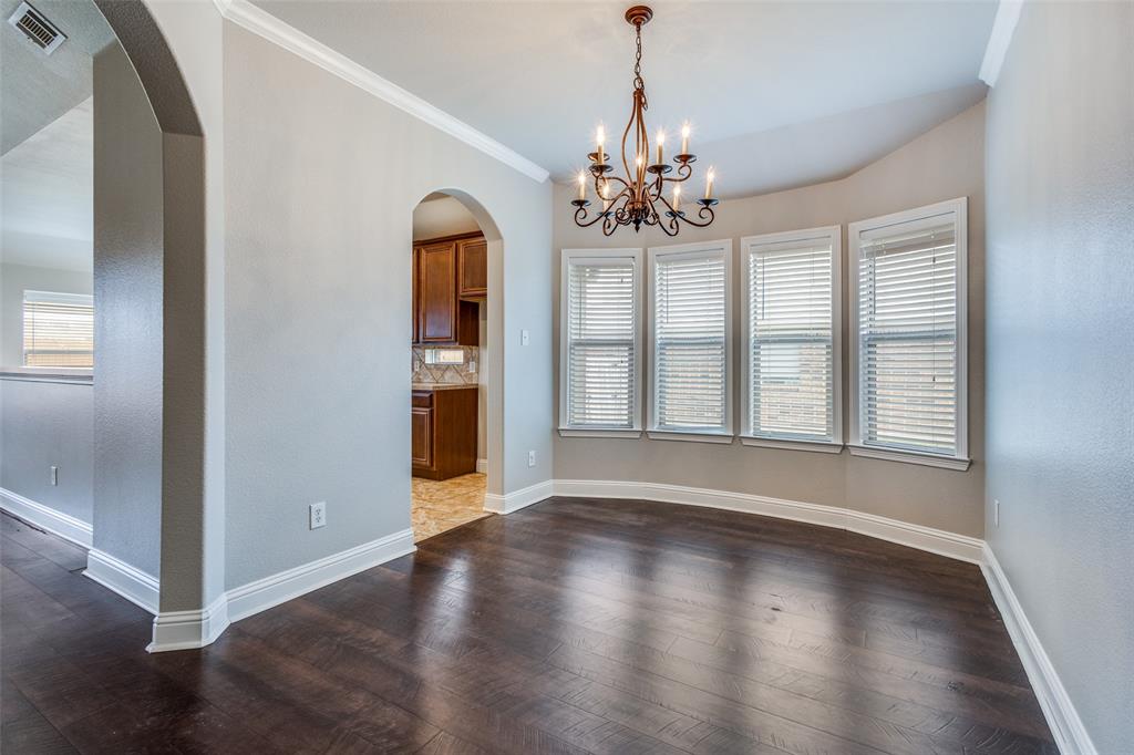 145 Mill Street Anna, TX 75409 - Photo 6 of 25 an empty room with wooden floor chandelier and windows