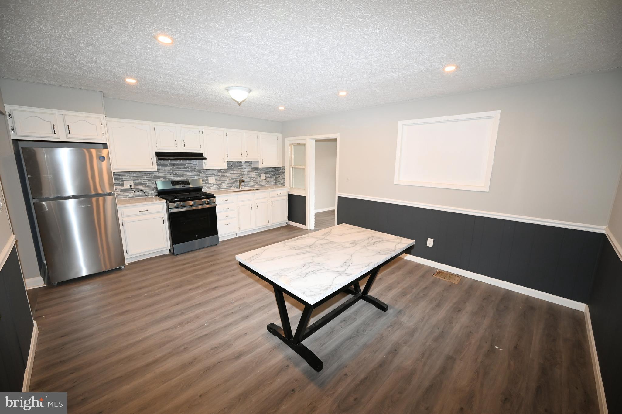 2952 Sollers Point Road, Unit B Dundalk, MD 21222 - Photo 22 of 37 a kitchen with stainless steel appliances granite countertop a refrigerator a stove a sink dishwasher and a refrigerator with wooden floor