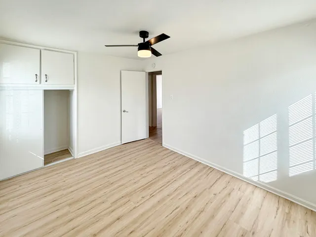 a view of empty room with wooden floor and fan