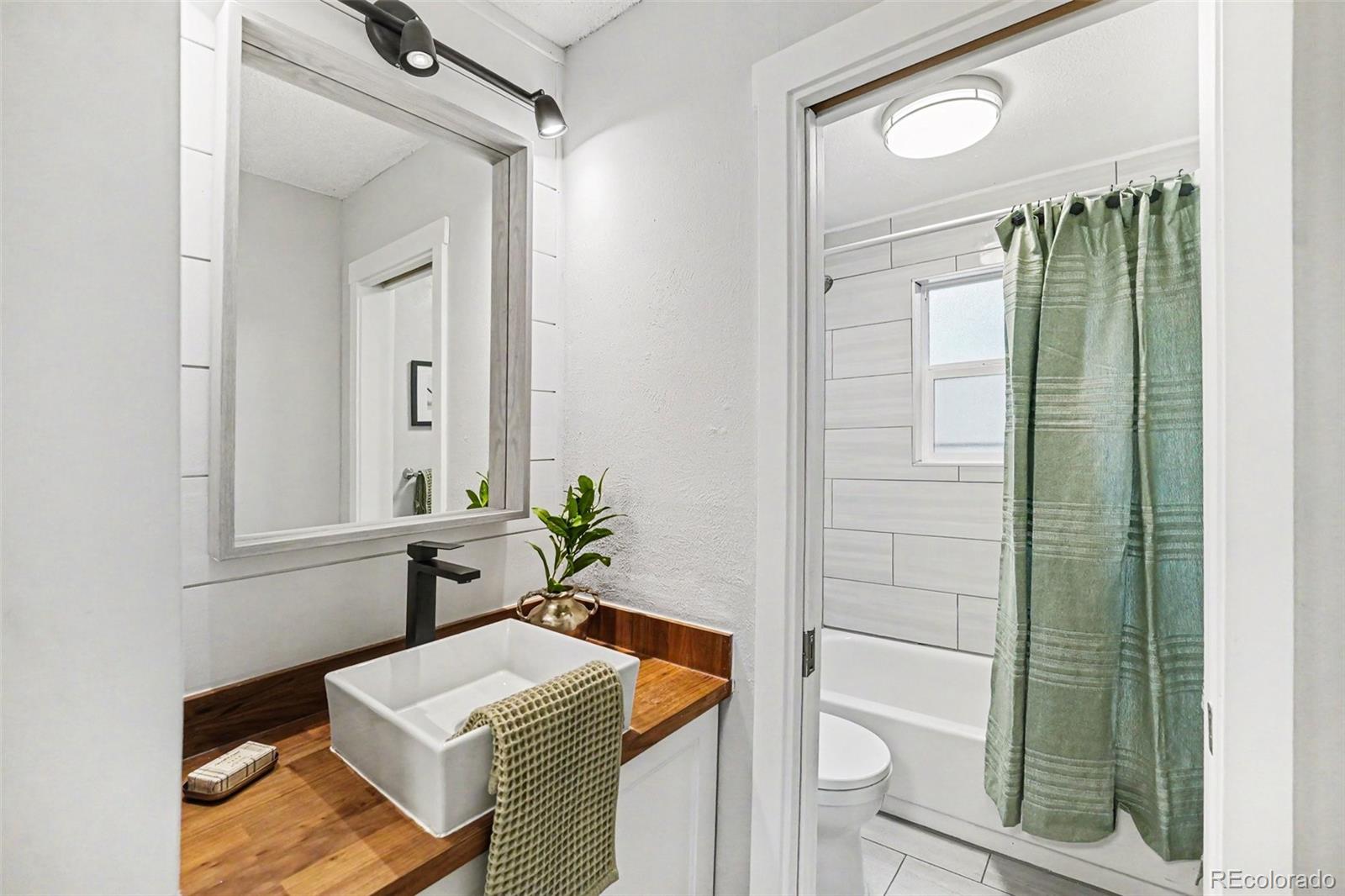5700 West 28th Avenue, Unit 1 Wheat Ridge, CO 80214 - Photo 8 of 25 a bathroom with a sink a toilet and shower