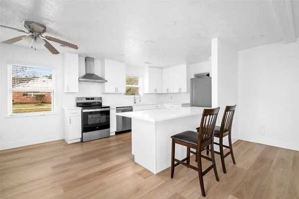 a kitchen with stainless steel appliances kitchen island a table chairs refrigerator and microwave