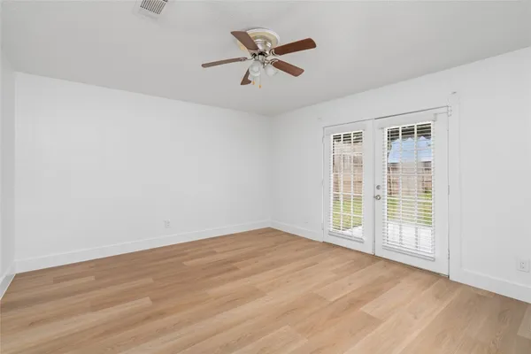 an empty room with wooden floor and ceiling fan