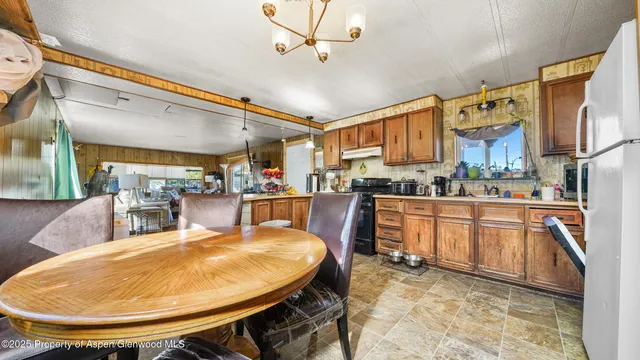 a kitchen with stainless steel appliances kitchen island granite countertop a table chairs and a wooden cabinets