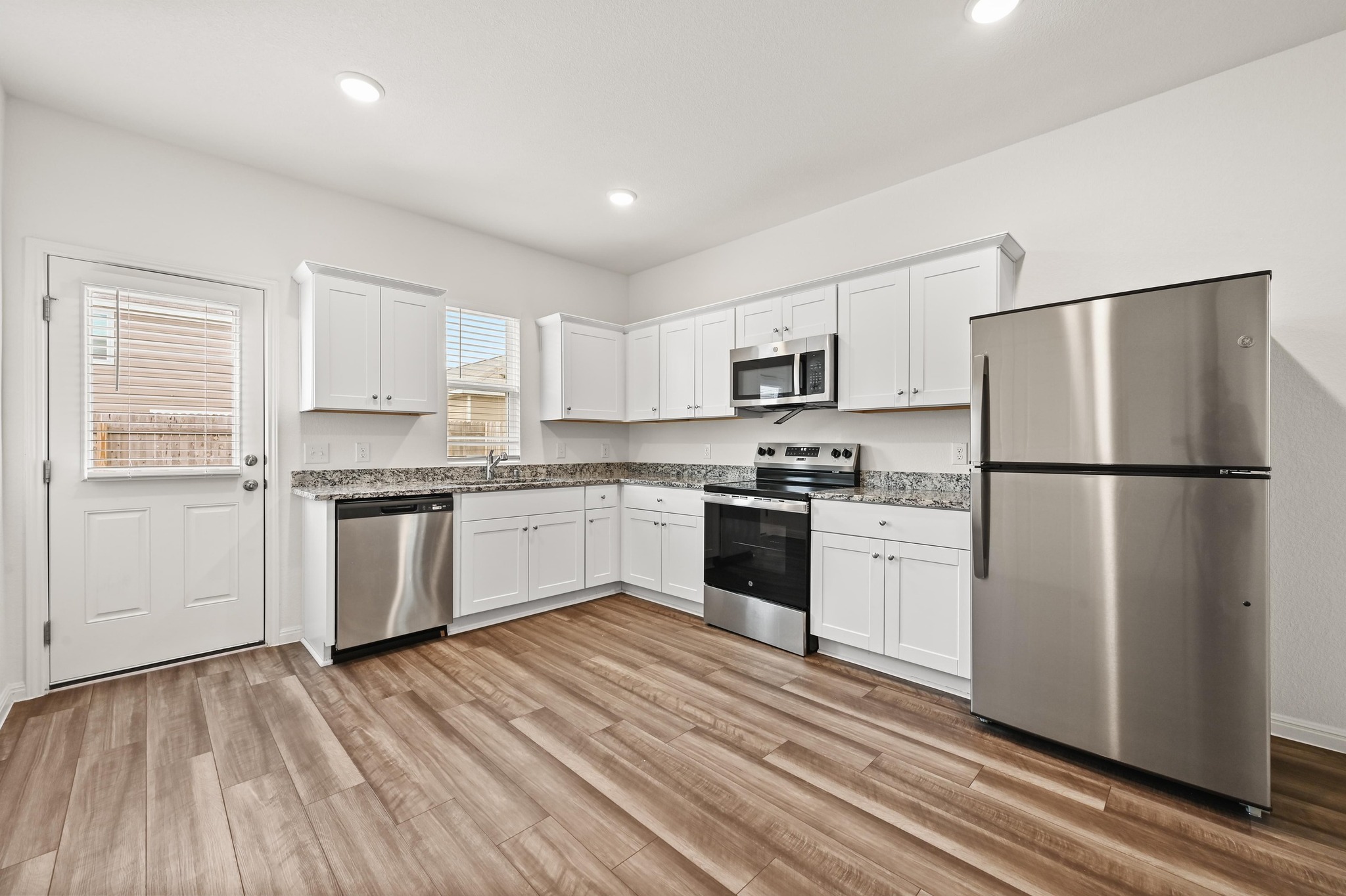 473 Thistle Lane Maxwell, TX 78656 - Photo 10 of 25 Kitchen with stainless steel appliances, white cabinets, light wood-style flooring, recessed lighting, and light stone counters