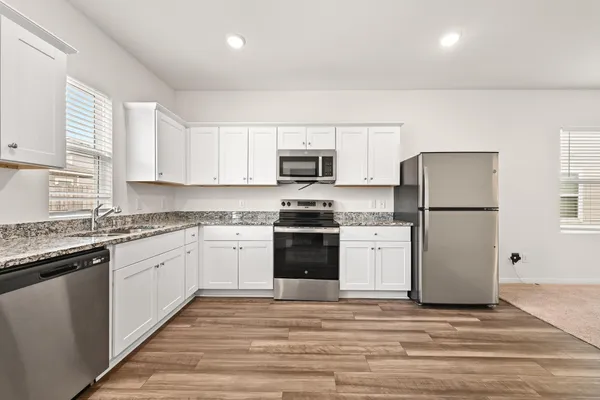 a kitchen with granite countertop a refrigerator stove top oven and sink