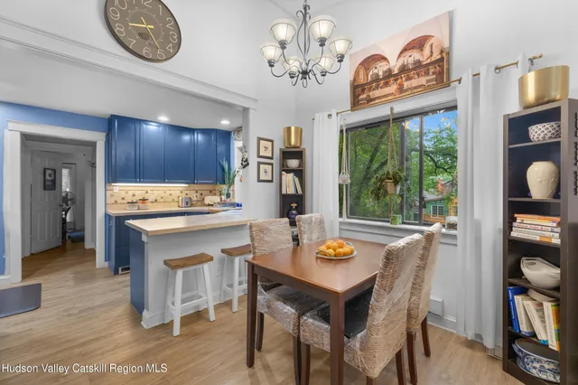 a open dining room with wooden floor a chandelier a wooden table and chairs