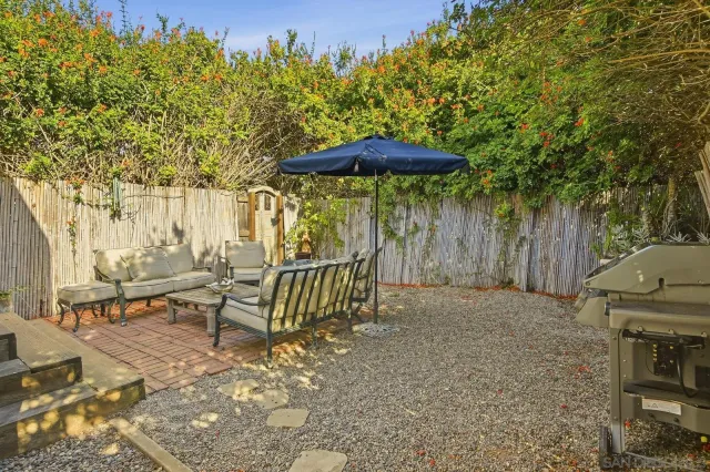 a view of a patio with a table and chairs under an umbrella with wooden fence