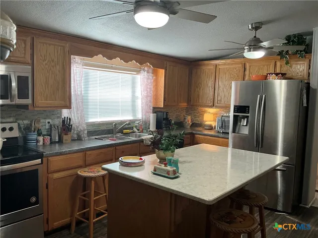 a kitchen with stainless steel appliances a dining table chairs and granite counter tops