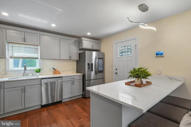 a kitchen with stainless steel appliances a sink a refrigerator and white cabinets