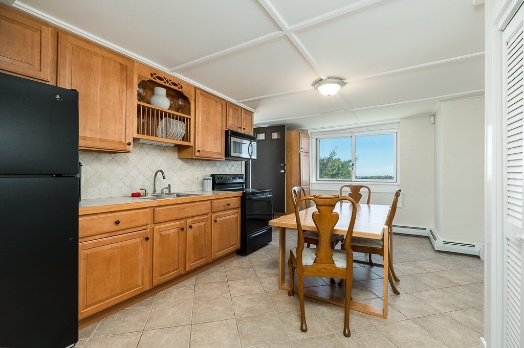 15 Cliff Road Gloucester, MA 01930 - Photo 30 of 42 a kitchen with stainless steel appliances kitchen island granite countertop dining table chairs and a refrigerator