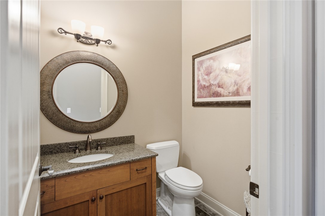 130 River Ridge Road Sunset, SC 29685 - Photo 28 of 47 This powder room features a custom vanity with granite countertops and a striking round mirror, illuminated by a decorative light fixture.