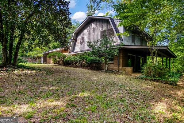 a front view of the house with a yard and trees