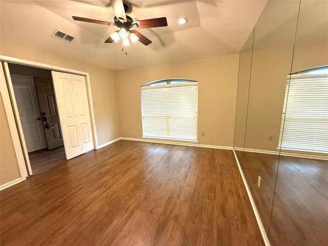 a view of empty room with wooden floor and fan