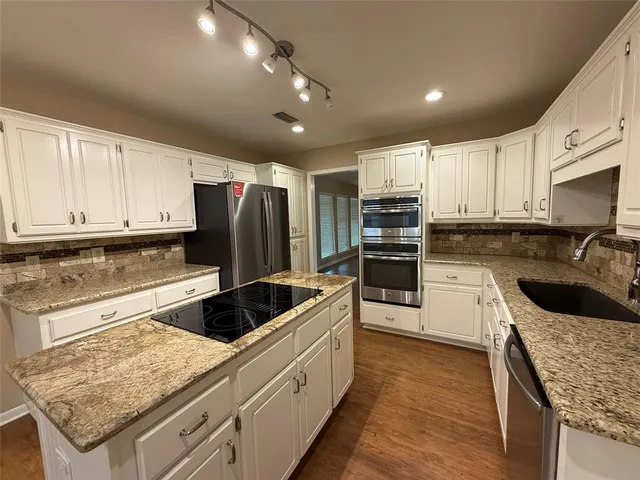 a kitchen with stainless steel appliances granite countertop a sink stove and refrigerator