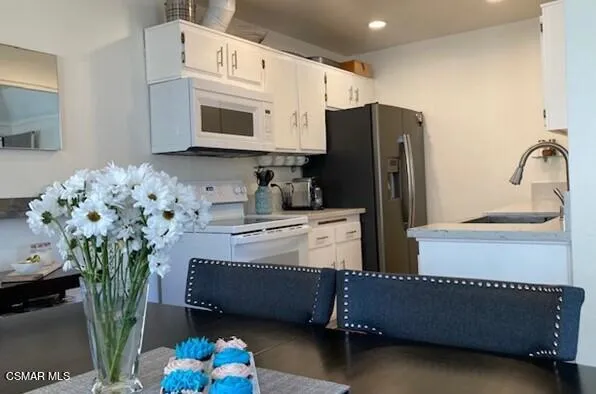 a kitchen with stainless steel appliances kitchen island granite countertop a refrigerator a stove a sink dishwasher and white cabinets with wooden floor