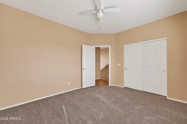 an empty room with a ceiling fan and carpet