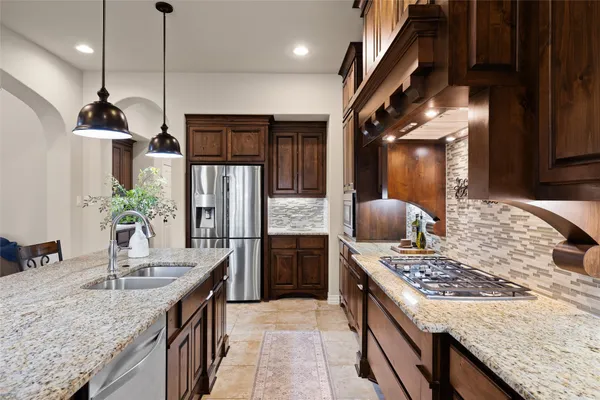 a kitchen with stainless steel appliances kitchen island granite countertop a refrigerator a stove a kitchen island a dining table and chairs