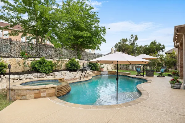 a swimming pool with lawn chairs under an umbrella