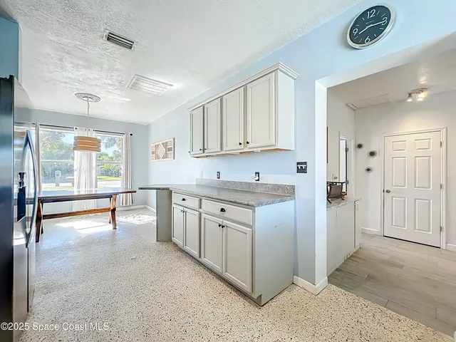 a kitchen with stainless steel appliances granite countertop a stove top oven a sink dishwasher a dining table and chairs with wooden floor