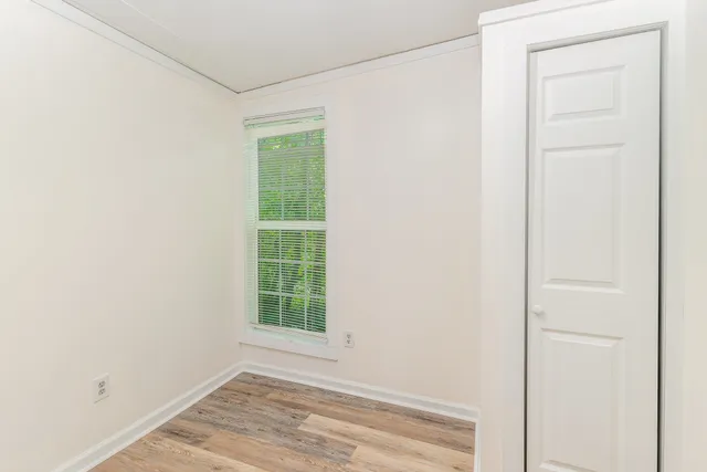 a view of an empty room with wooden floor and a window