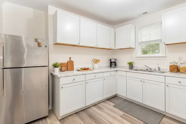 a kitchen with white cabinets white stainless steel appliances and sink