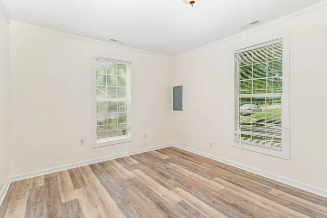 an empty room with wooden floor and windows