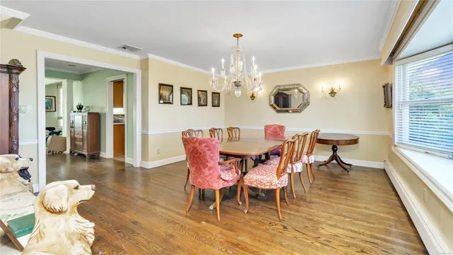 a dining room with wooden floor a chandelier a wooden table and chairs