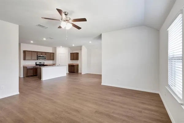 a view of an empty room with kitchen view and a window