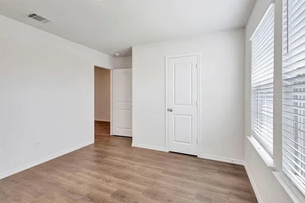 a view of an empty room with a window and wooden floor