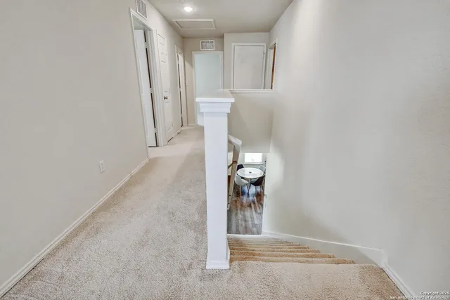 a view of a hallway with wooden floor and cabinets
