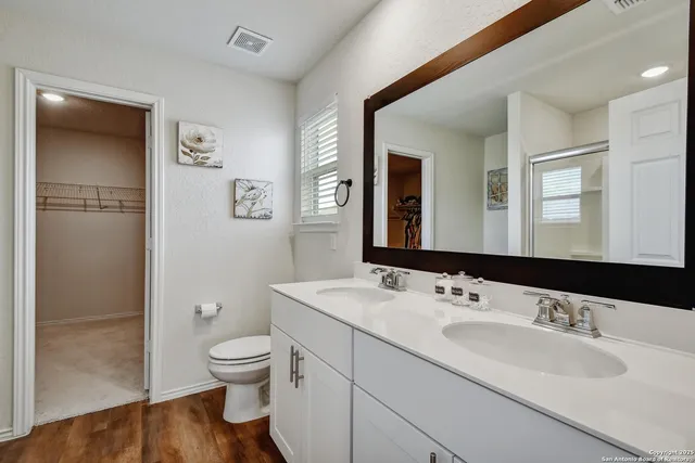 a bathroom with a toilet a sink a mirror and a shower